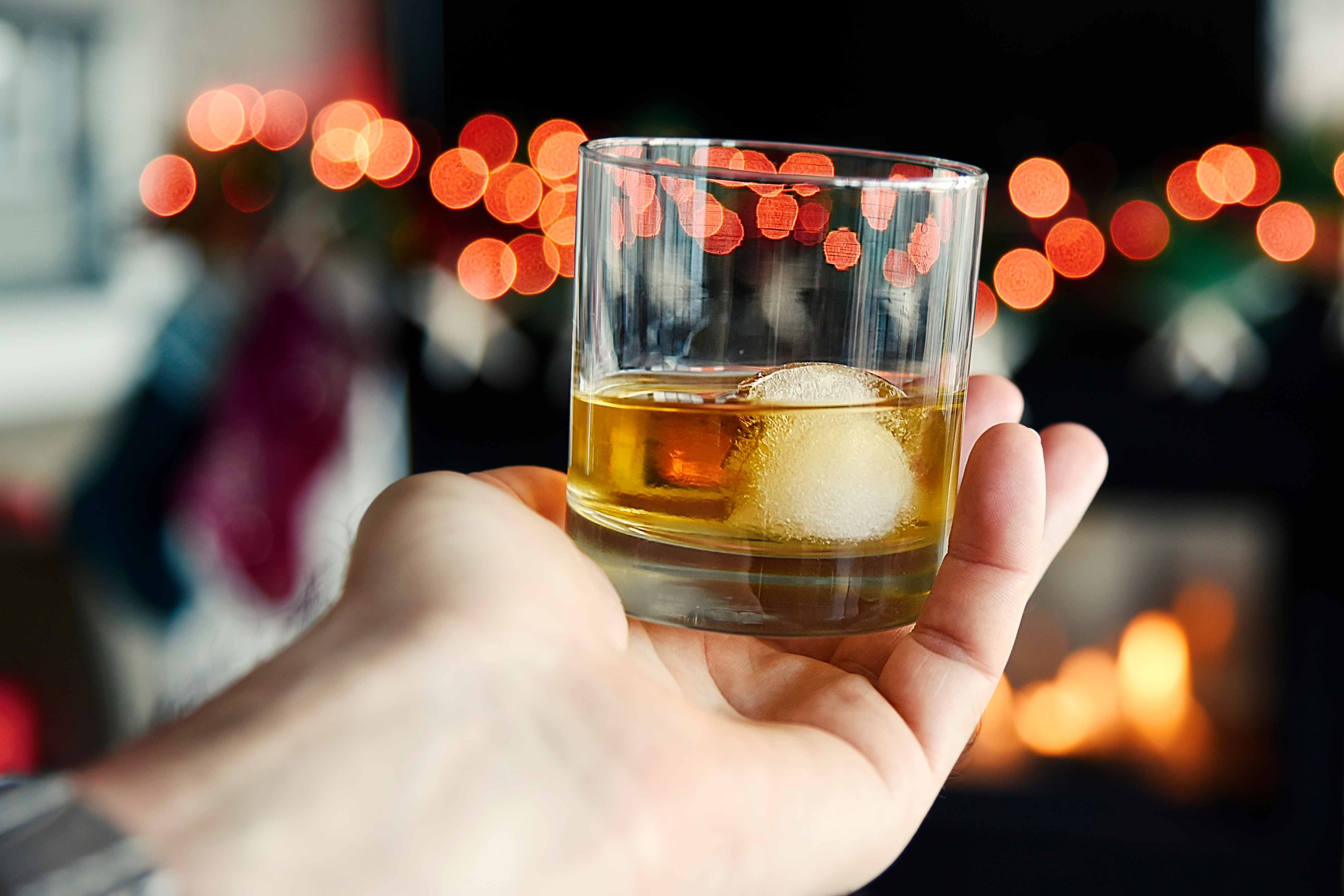 A person holding a drink in a room filled with Christmas decorations - learn how to avoid a DUI in Utah with tips from Branson West Law.