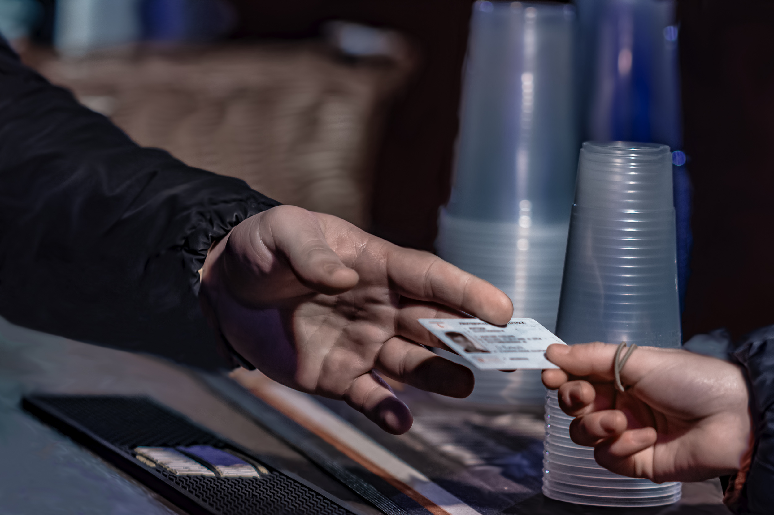 A person handing a bartender a fake ID.