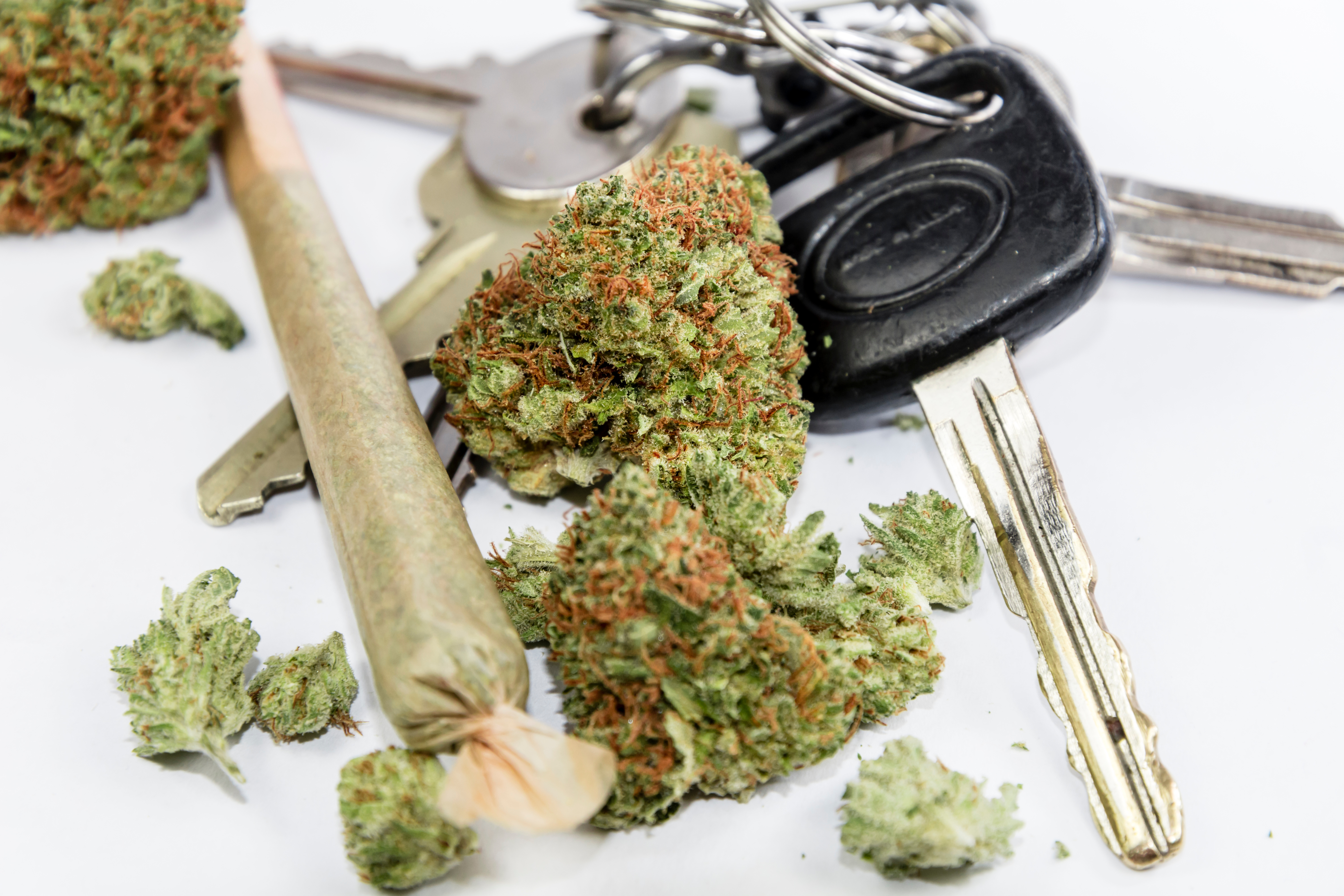 An image of marijuana buds and a rolled joint on a white surface next to car keys — For an expereinced marijuana DUI defense attorney in Utah, contact Branson West Law.